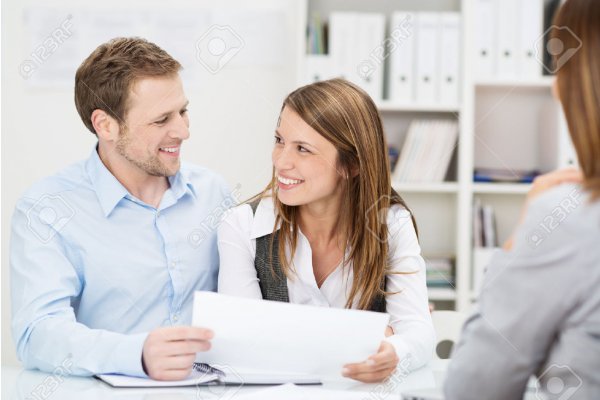 26572176-Young-couple-sitting-at-a-desk-in-the-office-of-their-agent-or-adviser-discussing-an-investment-pres-Stock-Photo_gallery.jpg